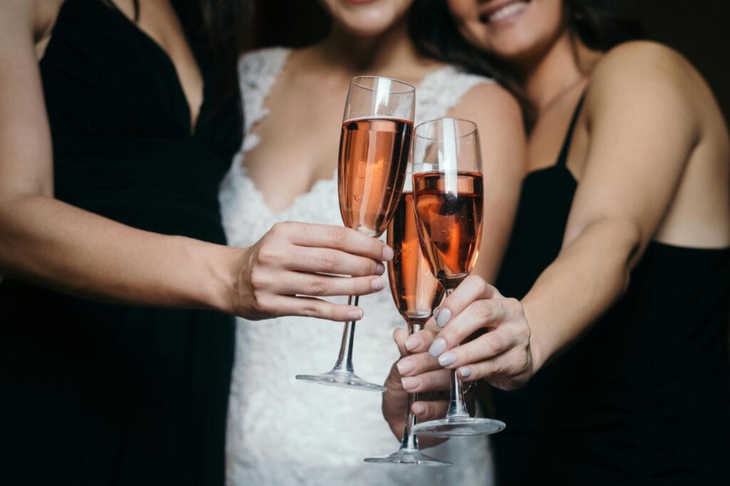pexels-photo-8459371-8459371 Three women toasting with rose wine glasses in a wedding celebration, captured up close.